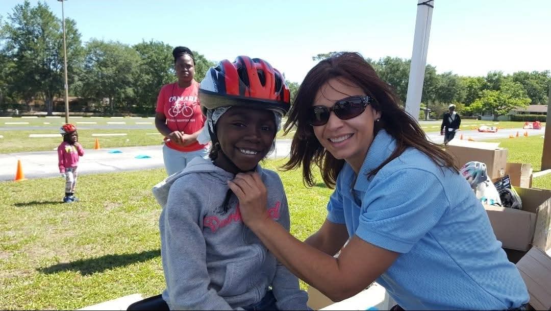 Marthaly fitting a child's bike helmet at a community safety event