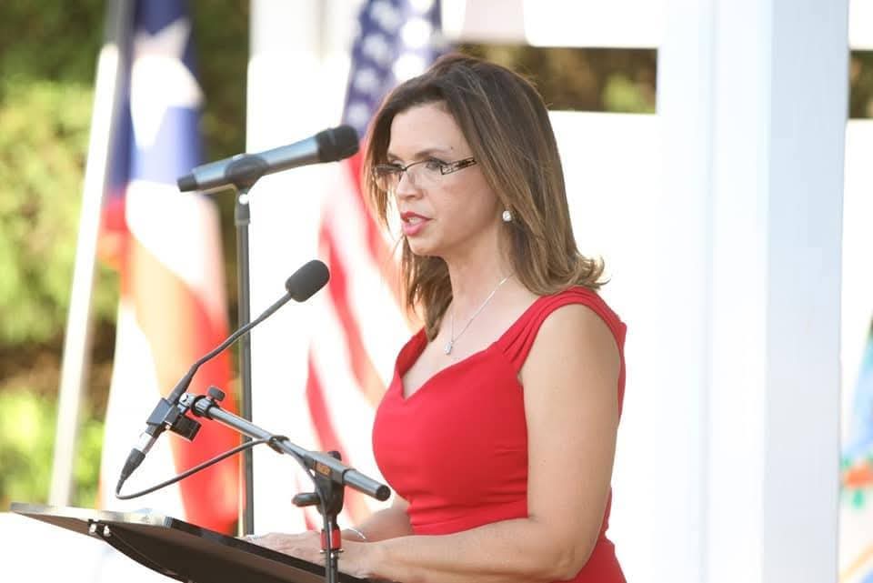 Marthaly speaking at a community event with American and Puerto Rican flags